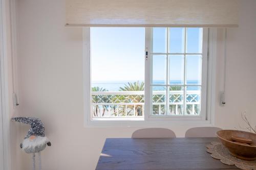 a dining room with a window with a view of the ocean at Apartamento LH Beach frente al mar in La Herradura
