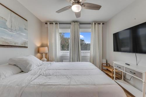 a bedroom with a bed and a flat screen tv at Three Little Birds in Kure Beach