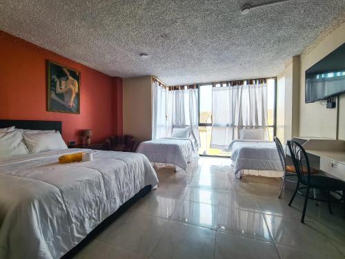 a hotel room with two beds and a desk at Hotel Las Americas in Cuenca