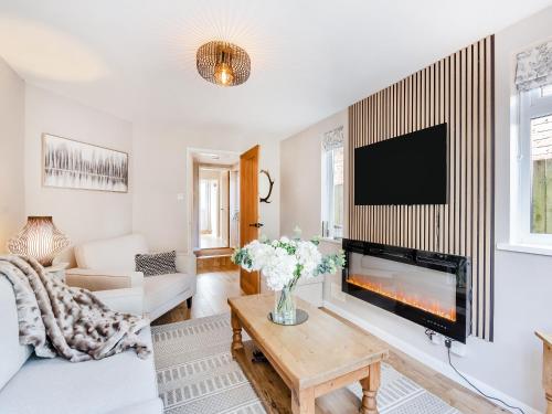 a living room with a fireplace and a tv at Wheelwright's Cottage in Yeaveley