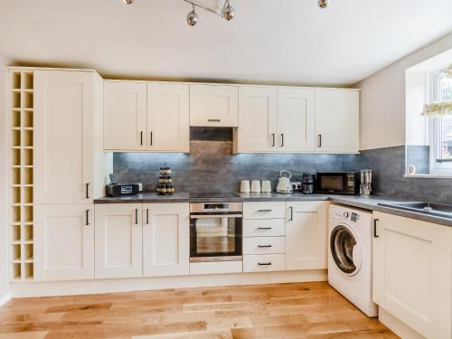 a kitchen with white cabinets and a washer and dryer at Wheelwright's Cottage in Yeaveley