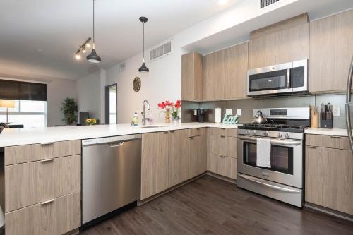 a kitchen with wooden cabinets and stainless steel appliances at Lovely 3BR Apt With Balcony And Rooftop Pool Plus Views in Los Angeles