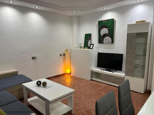 ein Wohnzimmer mit einer Couch, einem Fernseher und einem Tisch in der Unterkunft Apartamento espacioso El Olivo in Córdoba