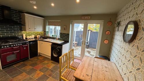 Il dispose d'une cuisine avec une table en bois et une cuisinière. dans l'établissement Hideaway cottage, à Kirkhamgate