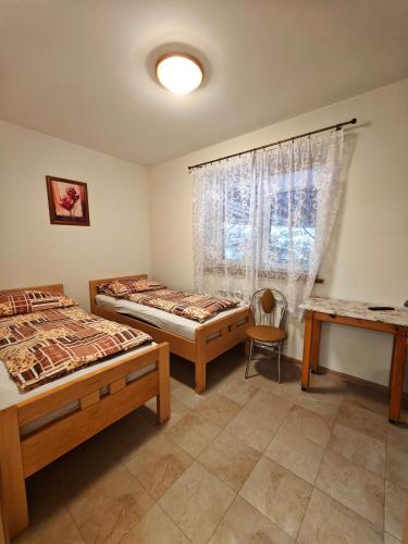 a bedroom with two beds and a table and a window at Domek nad wodospadem in Chochołów