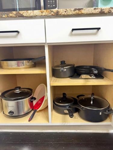 a kitchen cabinet with pots and pans on shelves at Cozy Home Apartments in Louisville