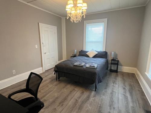 ein Schlafzimmer mit einem Bett, einem Stuhl und einem Kronleuchter in der Unterkunft One bedroom in a 4BR apartment in Lowell in Lowell