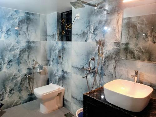 a bathroom with a white toilet and a sink at Roque's Place Goa in Betalbatim