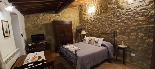 a bedroom with a bed and a table and a piano at La Corte Antica in Pienza