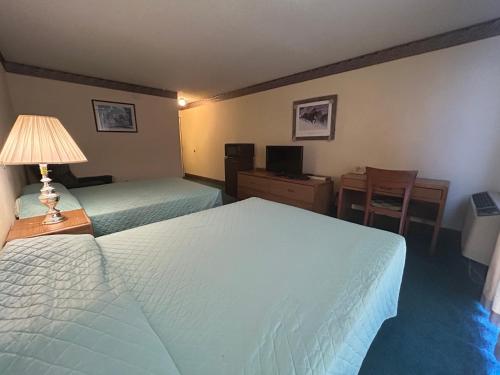 a hotel room with two beds and a desk at Candlelight Inn by Capital O Scottsbluff in Scottsbluff