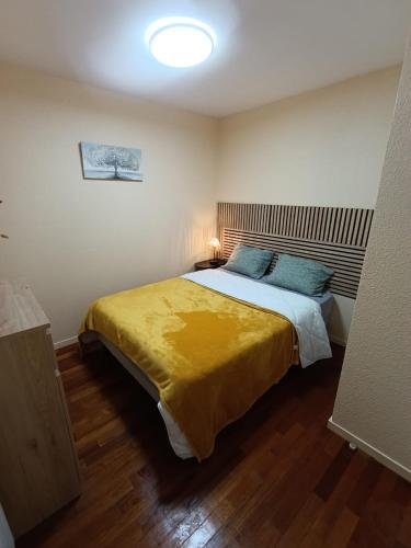 une chambre avec un grand lit avec une couverture jaune dans l'établissement Refuge du Renard au Bord du Lac, à Malbuisson