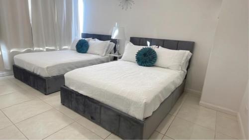 two beds with blue pillows in a bedroom at New Ocean View Condominium Free parking in Honolulu