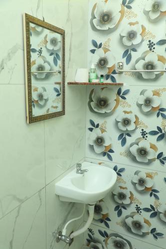 ein Badezimmer mit einem Waschbecken und einer blumengeschmückten Wand in der Unterkunft Sandy Toes -Ocean Balcony 2BHK & 2mins to Promenade in Puducherry