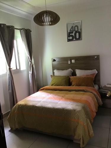 a bedroom with a bed with an orange and yellow comforter at Résidences MV in Kofa