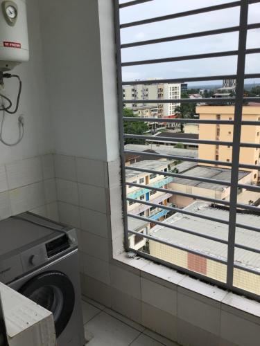 a laundry room with a window and a washing machine at Résidences MV in Kofa