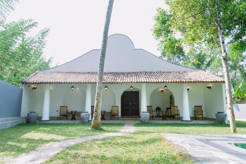 a small white building with a palm tree at Matt-Jay Villa -Baddegama in Baddegama