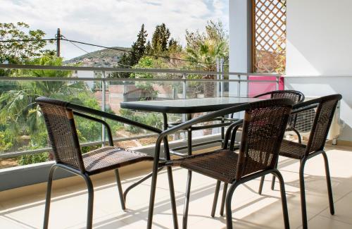 a glass table and two chairs on a balcony with a view at Elvita Spata Luxurious Villa in Spata