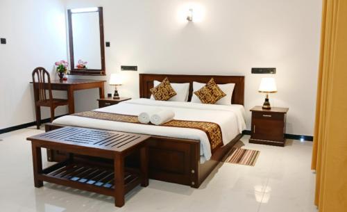 ein Schlafzimmer mit einem großen Bett und einem Tisch in der Unterkunft Coco Mount Residence - Hiriketiya in Dikwella