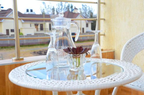 une bouteille en verre et un vase sur une table en verre dans l'établissement Jayhawk House, à Nairobi