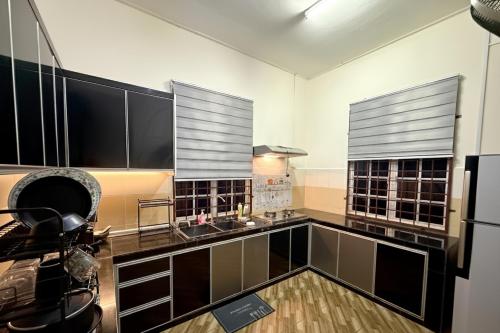 eine Küche mit schwarzen und weißen Schränken und einem Kühlschrank in der Unterkunft Misty Haven Homestay - Bungalow in Kuala Terengganu