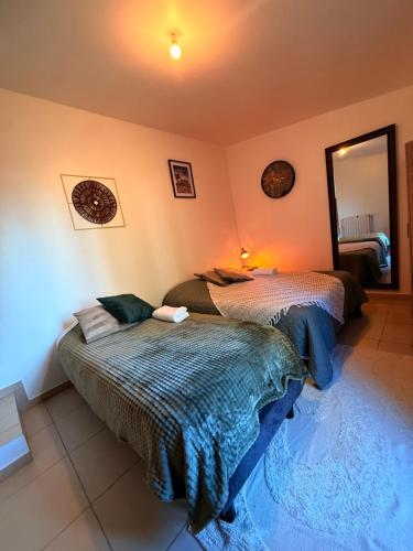 ein Schlafzimmer mit zwei Betten und einem Spiegel in der Unterkunft Maison Bon Séjour in Livry-Gargan