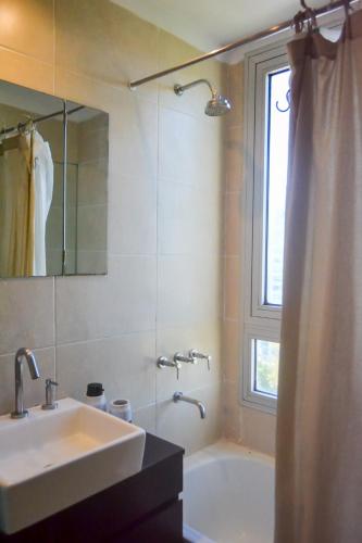 a bathroom with a sink and a tub and a window at 2 ambientes con Amenities y Vista al Río in Vicente López