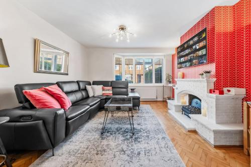 a living room with a black couch and a fireplace at Loudwater close in Sunbury Common