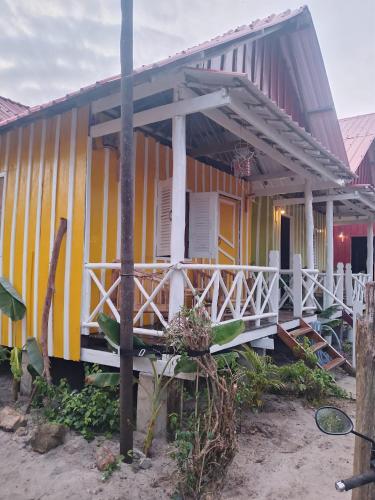 a yellow and white house with a porch at The Two Tigers - Sok San Village in Phumĭ Kaôh Rŏng