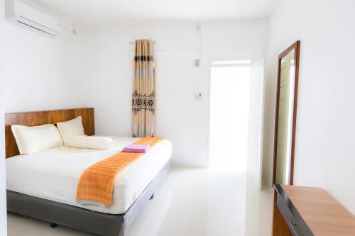 MeulabohNADA Homestay的一间带床和镜子的白色卧室