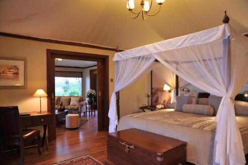 a bedroom with a canopy bed and a desk at Lake Elmenteita Serena Camp in Elmenteita