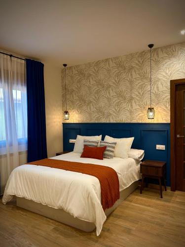 a bedroom with a large bed with a blue headboard at La villa de Ramona in Argamasilla de Alba