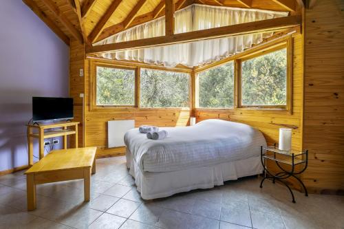 - une chambre avec un grand lit dans une cabane en bois dans l'établissement BOG Altos de Antilhue - Apart con vista al bosque, à Villa La Angostura