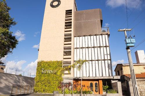 a tall tower with a clock on the side of it at Get Sense #306 - Beira mar por Carpediem in Tambaú