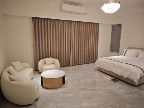 a bedroom with a bed and a couch and chairs at 莉莉安の家 6-13人包棟 in Wujie