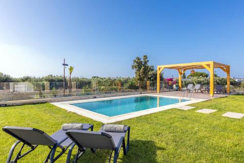 a swimming pool with chairs and a gazebo at Villa Sandi with Private Pool in Hersonissos