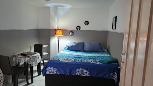 a bedroom with a bed with blue sheets and a table at Aparta estudio Fantástico in Bucaramanga