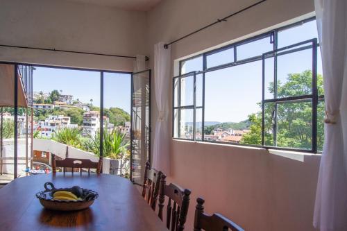 a table with a bowl of bananas on it in a room with windows at Casa del Rey in Taxco de Alarcón