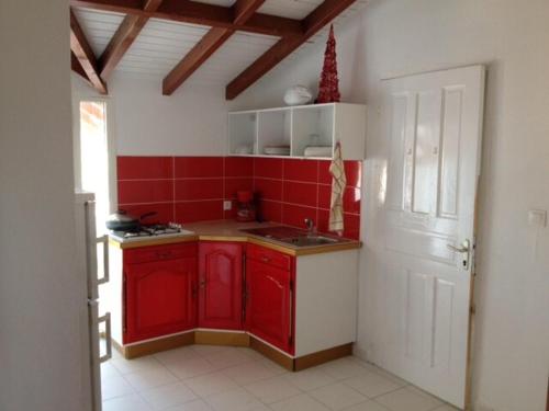 eine Küche mit roten Schränken und einer roten Fliesenwand in der Unterkunft Corail rouge in Sainte-Anne