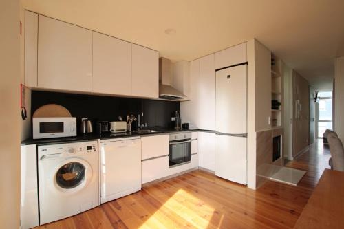a kitchen with white cabinets and a washer and dryer at OPORTO GUEST Natária Flats with Parking in Porto