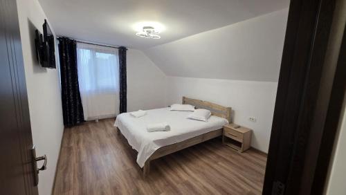 a bedroom with a white bed and a window at Pensiunea Heaven in Dîmbovicioara