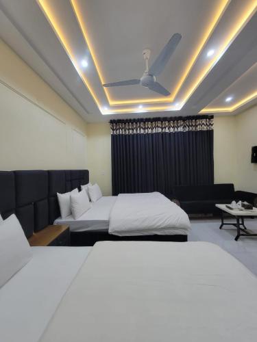 a hotel room with two beds and a couch at Airport Gateway Guesthouse in Rawalpindi