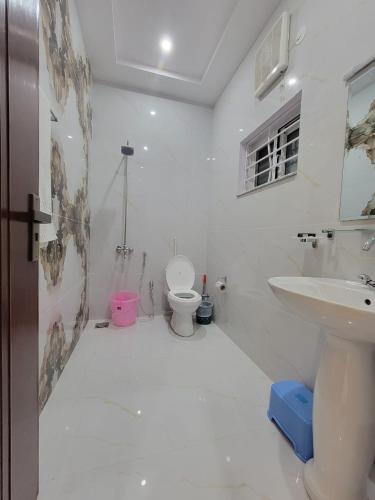 a white bathroom with a toilet and a sink at Airport Gateway Guesthouse in Rawalpindi