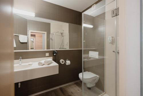 Un baño con lavabo, inodoro y ducha. en Sporthotel Kapfenberg, en Kapfenberg
