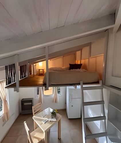 a loft bed in a tiny room with a desk and a bed at La Perla - Centro de El Bolsón. in El Bolsón