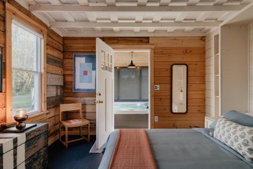 1930's Vintage Cabin Hot Tub Kohler Cabin في Jeffersonville: غرفة نوم بجدران خشبية وسرير ونافذة