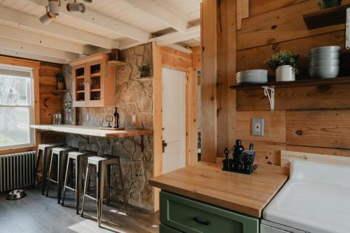1930's Vintage Cabin Hot Tub Kohler Cabin في Jeffersonville: مطبخ بجدران خشبية وكاونتر مع الكراسي