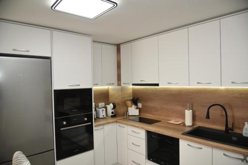 eine Küche mit weißen Schränken und einem schwarzen Gerät in der Unterkunft C&A Apartment in Goze Deltschew