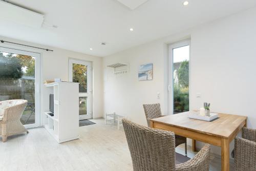 a dining room with a wooden table and chairs at D4 Bungalow - Haus Dünenpark Königsberger Allee 12 - FERIENDOMIZIL HOLLICH in Grömitz