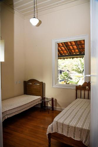 a room with two beds and a window at Chácara no centro para até 15 pessoas com piscina aquecida e 5 quartos in Duas Barras