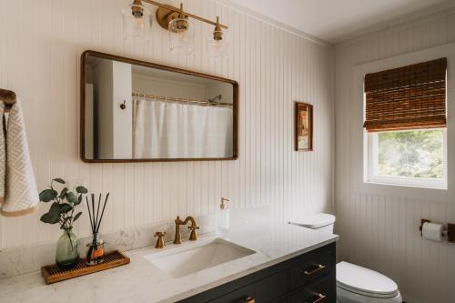 une salle de bain avec un lavabo, des toilettes et un miroir dans l'établissement Roebling House 1850s Cabin Hot Tub Fire Pit, à Lackawaxen